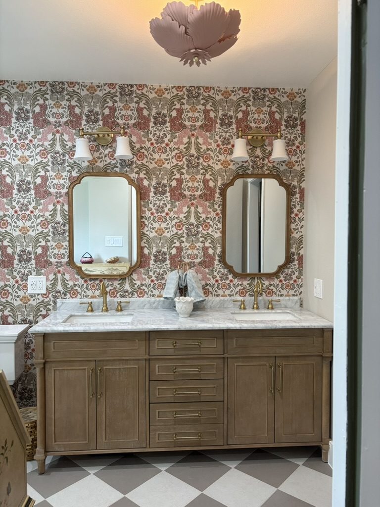 After: wood double vanity with marble top, gold mirrors, and a blush petal ceiling light in a remodeled Dallas bathroom