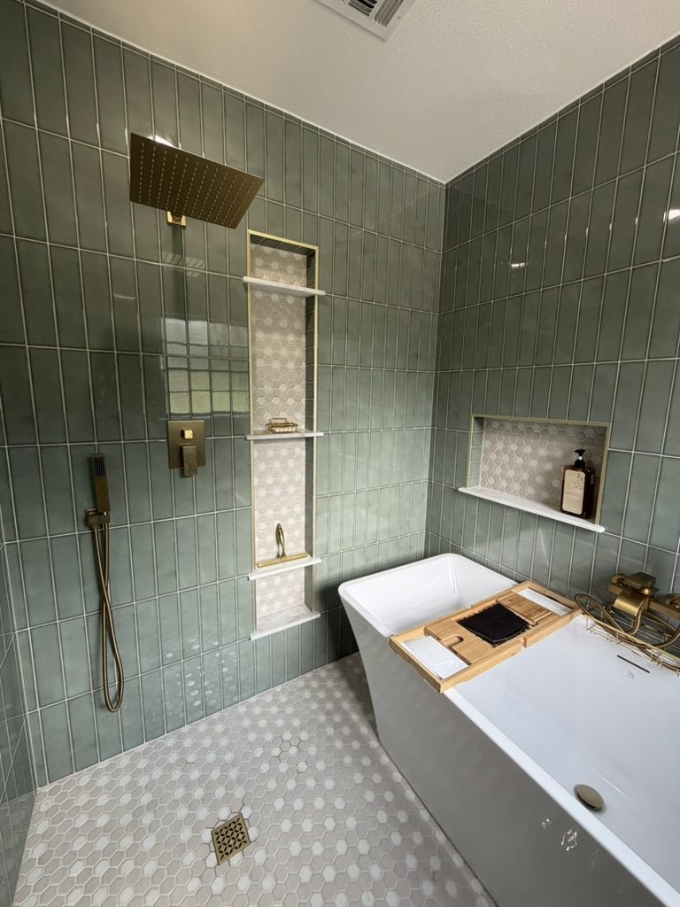 After: brass rain shower and handheld sprayer, tall shower niche, and hex mosaic floor in a sage tile wet room